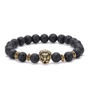 Macro shot of lava stone beads and detailed gold lion head charm on an elastic bracelet