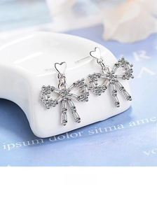 Detail of bow-shaped drop earrings with S925 silver and cubic zirconia heart studs