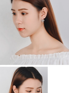 Close-up of a silver bow earring with zircon stones worn by a model in a minimalist style