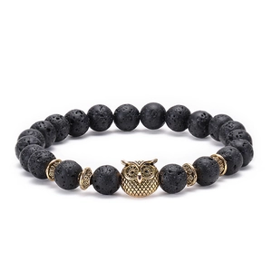 Detail of beaded bracelet with black lava stone beads and a gold owl charm pendant
