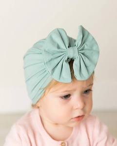 Close-up of mint green knit baby turban hat with a large bow detail and soft texture