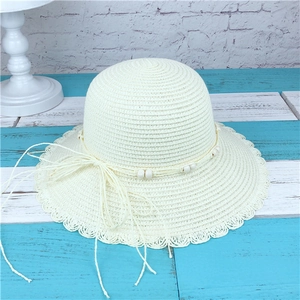 Detail of woven straw sun hat featuring elegant bead trim and wavy scallop edge brim