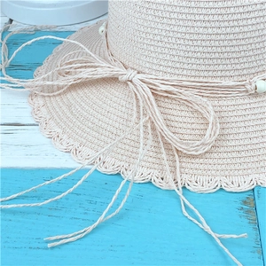Women's pink woven straw sun hat with scalloped edges and bead bow detail for beach