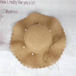 Straw beach sun hat with wide wavy brim and elegant white pearl bow decoration