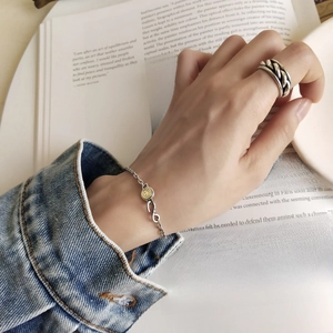 Detail of vintage silver smile face bracelet and woven ring worn by hand model