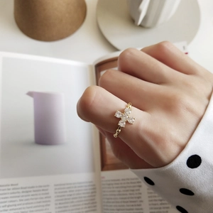 Detail of a minimalist gold ring with four pear-cut zircon stones in a floral cross design