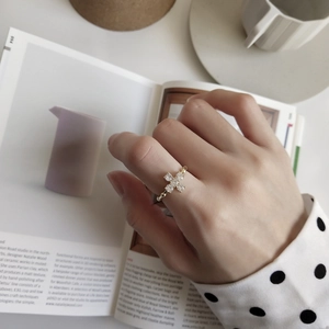 Close-up of a gold cross ring with white crystals on an open book, minimalist style