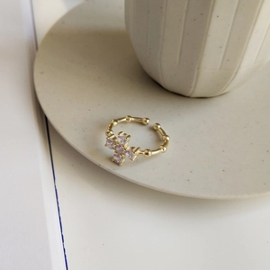 Detail of gold bamboo ring featuring lavender heart zircon cross on ceramic tray