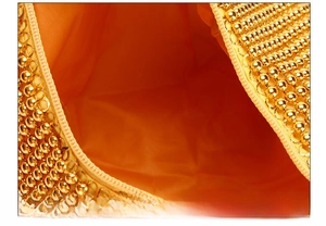 Detail of evening clutch featuring golden bead exterior and orange satin lining with zipper
