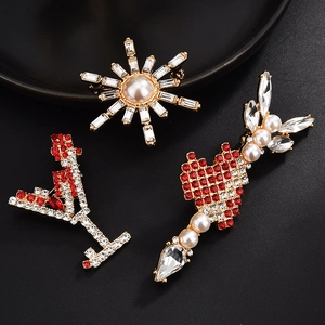 Detailed view of three alloy brooches with rhinestones and pearls on a black background