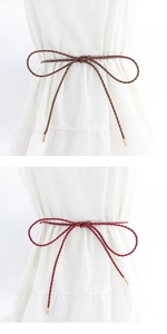 Detail of woven PU waist ropes in brown and burgundy with gold metal tips on white dress