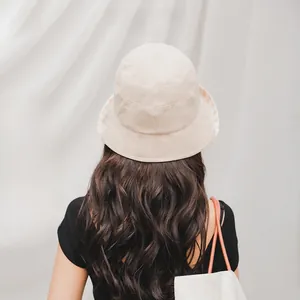 Rear view of a minimalist beige bucket hat on a model with a clean aesthetic background