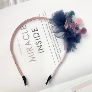 Detail of kids headband featuring a blue mesh flower with glitter crown and colorful pom poms