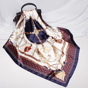 Detail of silk-like scarf with equestrian chain print draped on black handbag