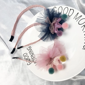 Set of 2 sequin crown headbands with tulle and colorful pom-poms on a white dish