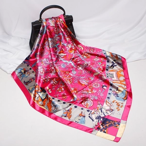 Detailed view of luxury silk-style scarf with multi-color print draped on a leather handbag