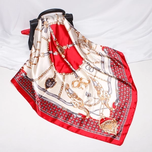Detail of silk scarf with classic chain print draped over a black luxury handbag