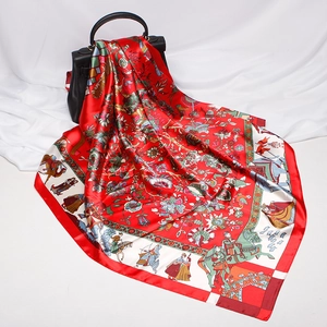 Detailed pattern of red silk scarf with floral and rider prints on a black leather handbag