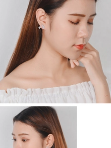 Close-up of elegant leaf-shaped silver earrings with sparkling zircon on model ear