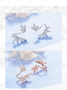 Macro detail of leaf-shaped silver and rose gold earrings with zircon settings