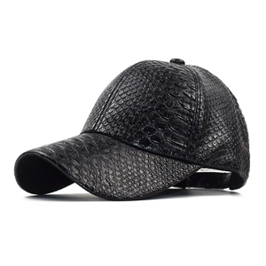 Macro detail of black baseball cap featuring textured faux crocodile skin and curved brim