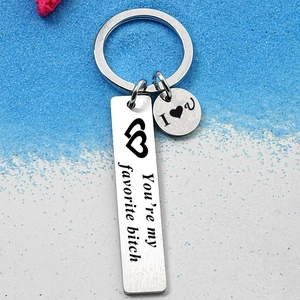 Silver stainless steel keychain with engraved heart and text on beach sand background