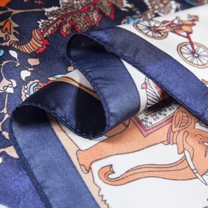 Macro detail of silk scarf showing elephant and floral patterns with hand-rolled edges