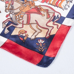 Detailed close-up of equestrian silk scarf with red and blue patterns and rolled edges