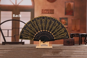 Back view of black folding fan with gold embroidery lace on vintage wood table