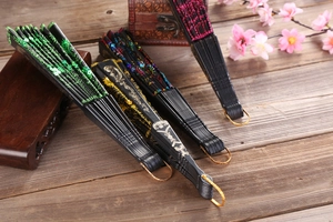 Detailed close-up of embroidered folding fans with sequins and peacock feather patterns