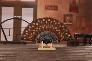 Detail of black folding fan with orange sequins and embroidered peacock feather patterns