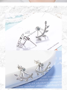 Detail view of silver branch leaf earrings with sparkling white crystals and studs
