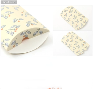 Detail view of a floral yellow pillow gift box featuring blue leaves and orange berries