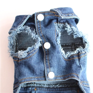 Close-up of denim dog vest with frayed edges and metal snap buttons details