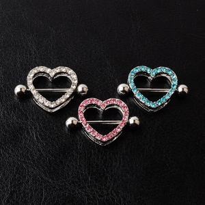 Detail of heart nipple shields with clear, pink, and blue crystals on dark surface