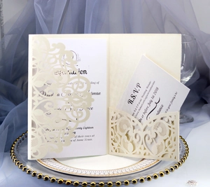 Detail of beige laser-cut floral lace wedding invitation and RSVP card on elegant tray