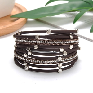 Close-up of layered brown leather bracelet with silver chains and sparkling crystals