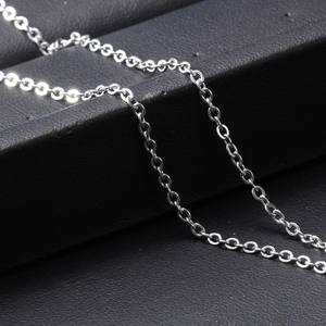 Detail of silver chain necklace with crown pendant displayed on black textured stand