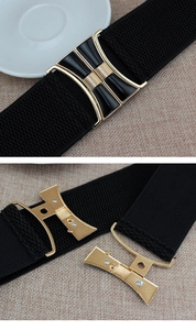 Close-up of black elastic waist belt featuring a gold-edged enamel interlocking buckle