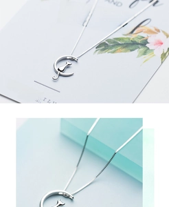 Macro view of silver crescent moon and cat silhouette pendant on minimalist box chain