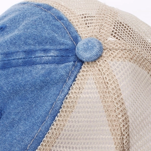 Detail of blue denim and beige mesh panels on a distressed vintage baseball cap