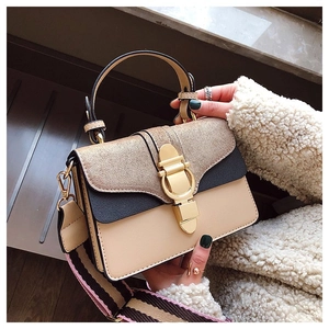 Detail view of stylish拼接handbag featuring gold buckle and striped woven strap