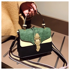 Close-up of retro color-block handbag with green suede flap and gold metal buckle