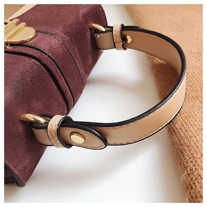 Macro detail of wine red suede handbag with cream leather handle and gold hardware