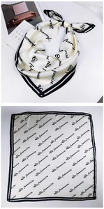 Close-up of cream satin square scarf with black cursive script print and bordered edges