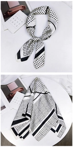 Close-up of elegant white silk scarf with black polka dots and satin glossy finish