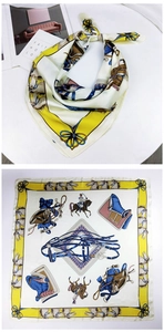 Detailed flat lay of a 70cm square silk scarf with yellow and blue equestrian patterns