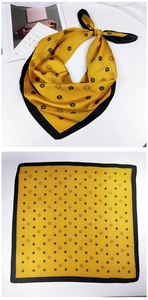 Detail view of yellow silk square scarf with black floral camellia patterns and border
