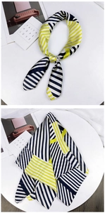 Detail of geometric striped silk scarf with black white and yellow patterns tied on a stand