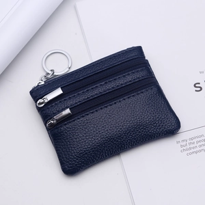Detail view of dark blue pebble leather coin purse with double zippers and silver keychain
